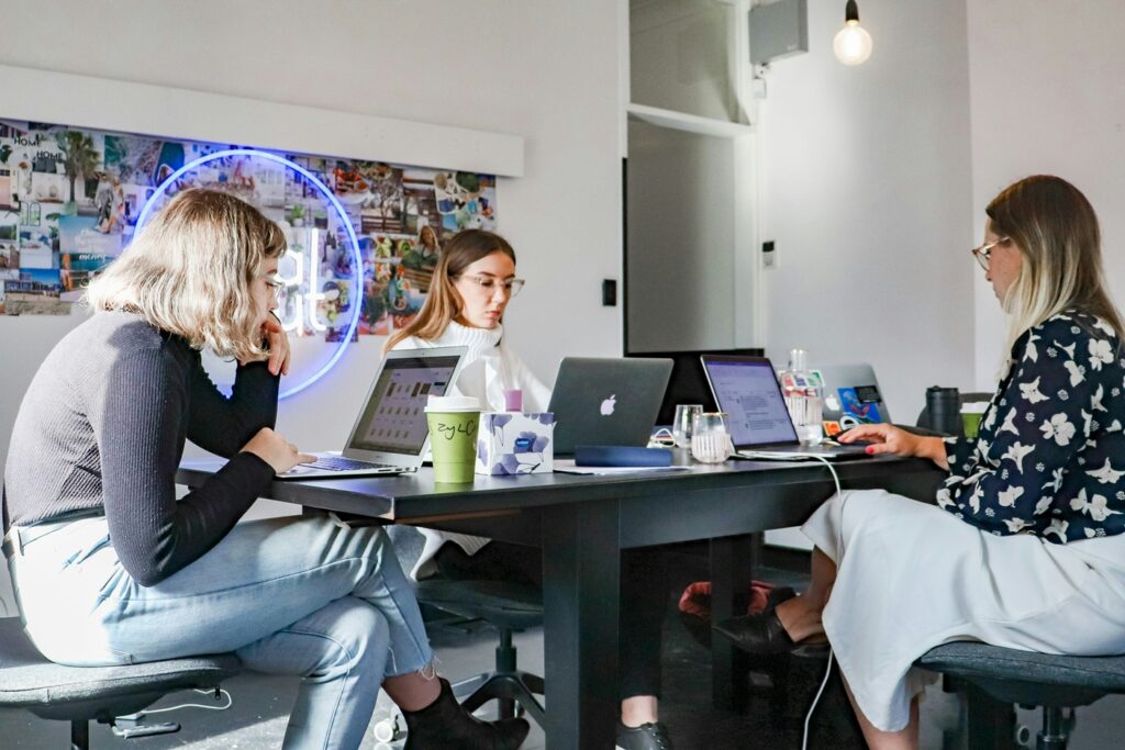 Two ladies and a guy using laptops