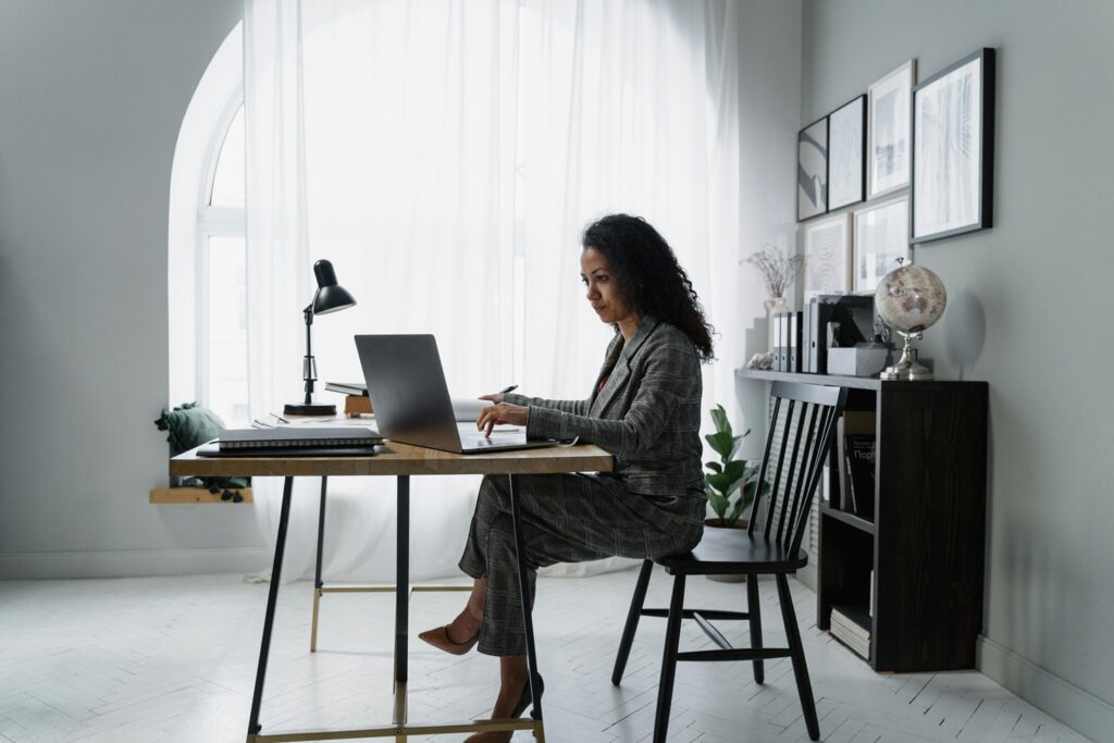a woman sitting at a desk working on the laptop computer