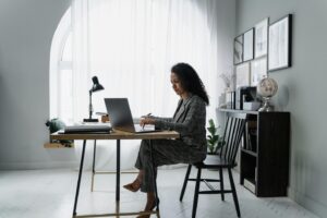 a woman sitting at a desk working on the laptop computer