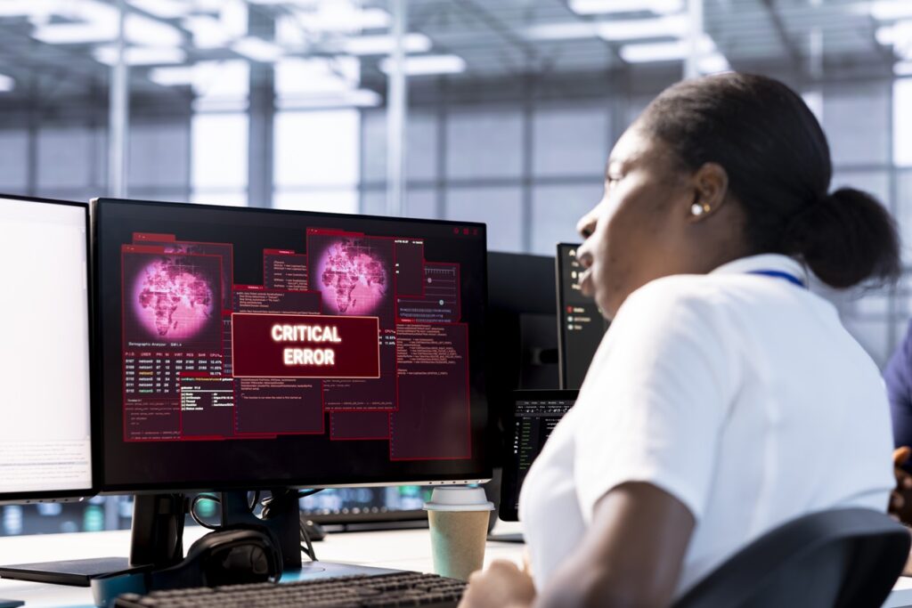 engineer in server hub investigating breach alerts, working to protect equipment