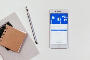 Home table with facebook open on mobile phone, pen and notepad